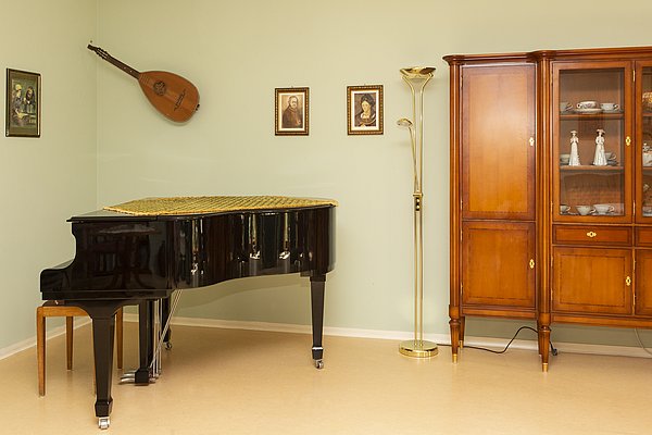Flügel in einer Ecke des Wohnzimmers, daneben eine Stehlampe und ein Holzschrank