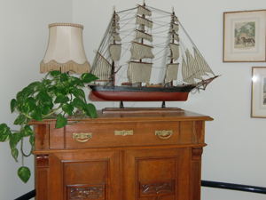 Kommode einer Bewohnerin oder eines Bewohners mit Segelschiffmodell und einer Pflanze darauf